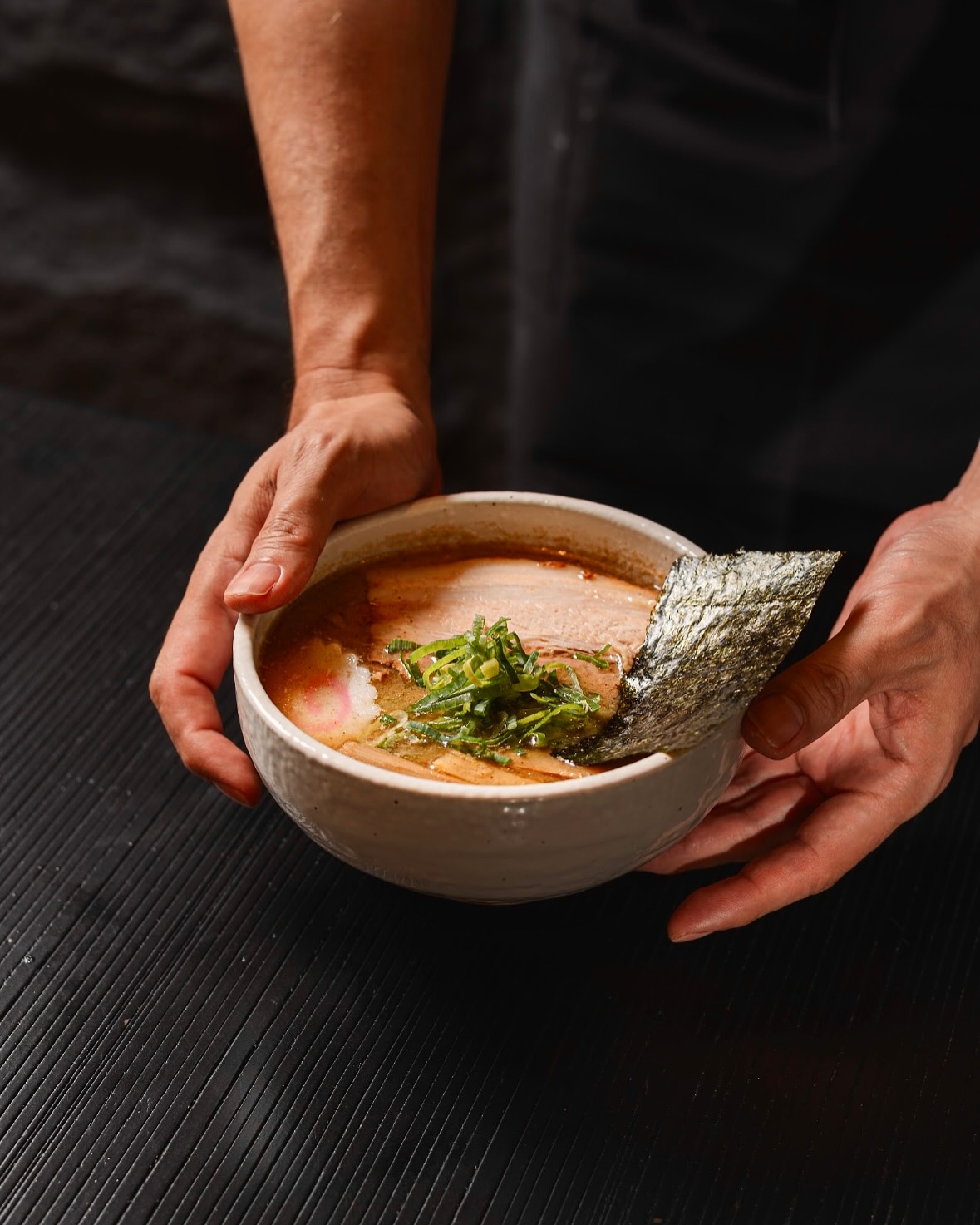 Chef presenting a bowl of INOSHO signature ramen
